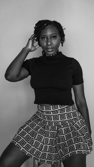 Studio portrait in black and white showing a graceful pose in a geometric patterned circle skirt and black top.