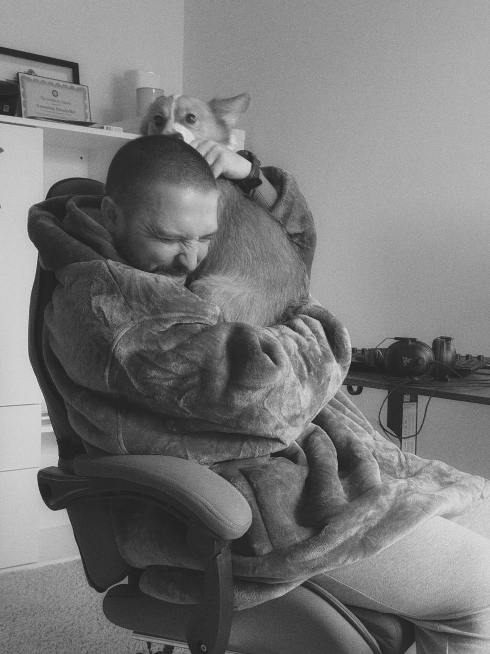 Person relaxing in office chair while cuddling with a cat in a cozy indoor setting.