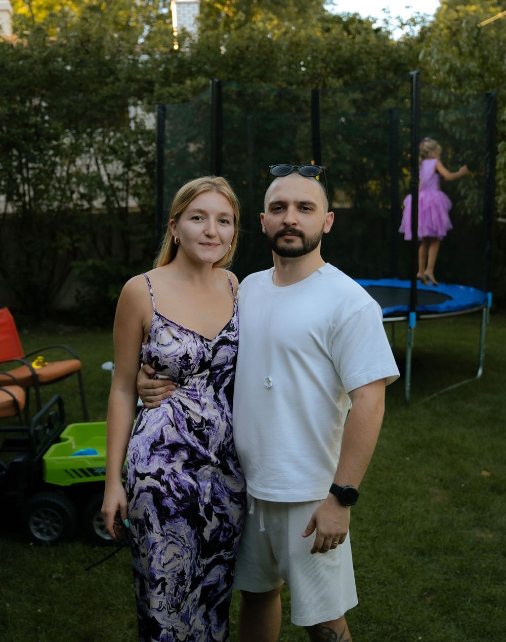 Backyard gathering with children playing on trampoline.