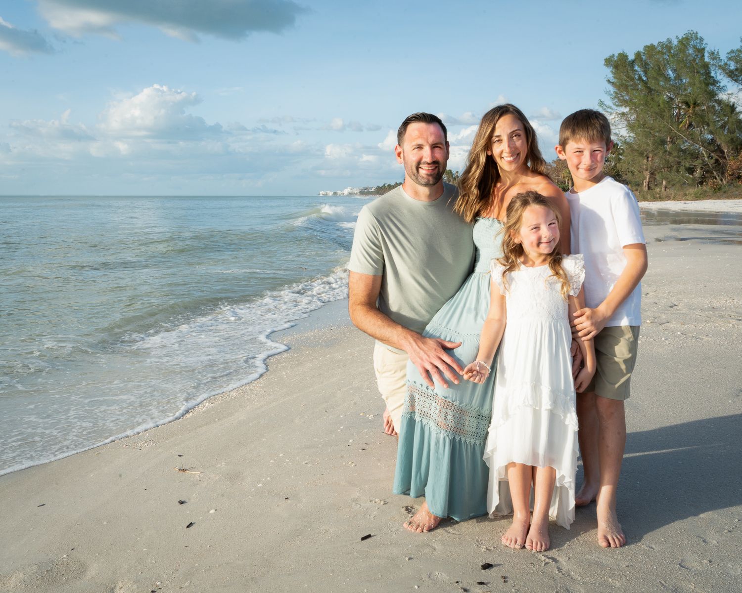 Beach family photography session with coordinated outfits showing playful moments by the ocean.