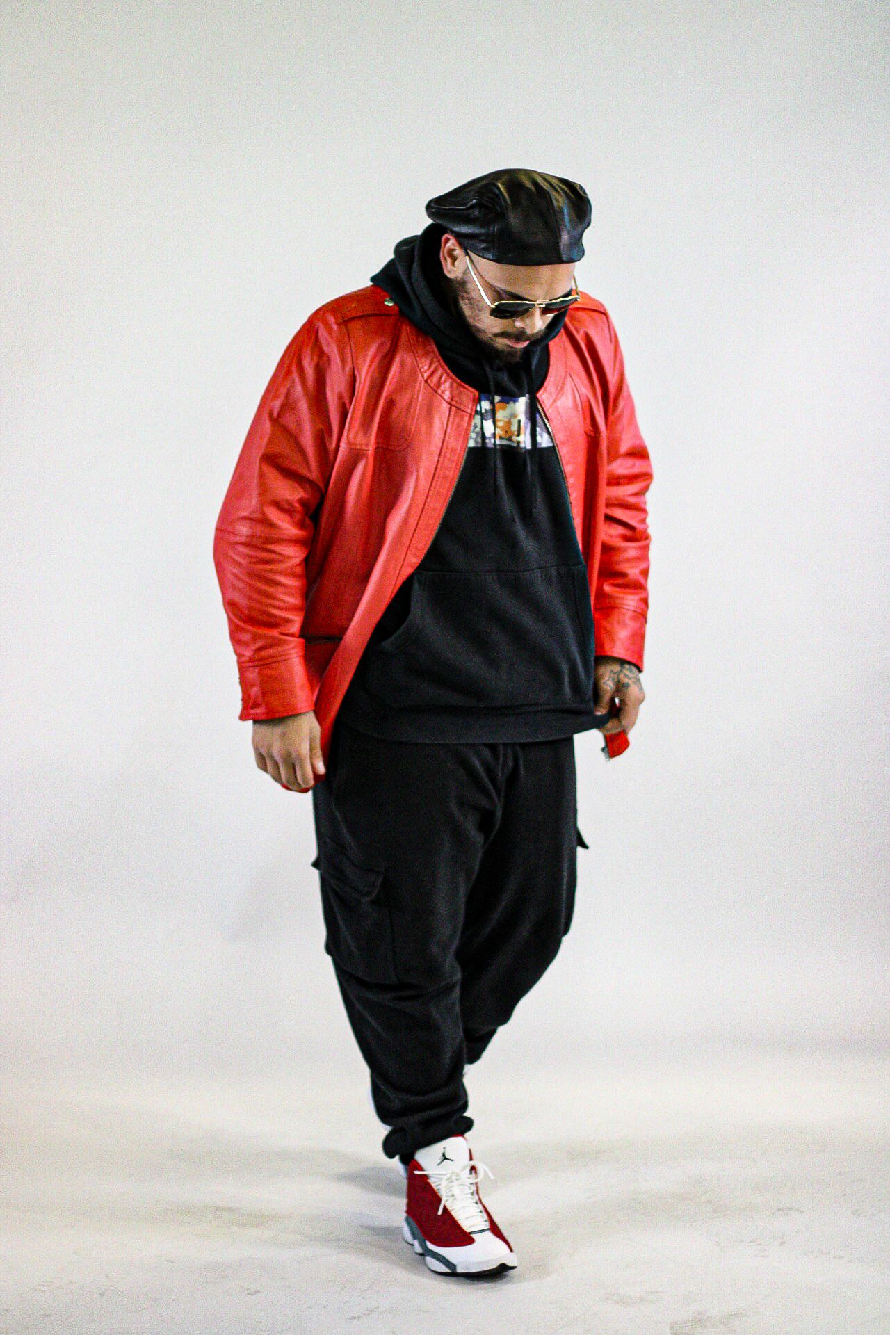 Fashion shoot of person in red jacket and black outfit against white background.