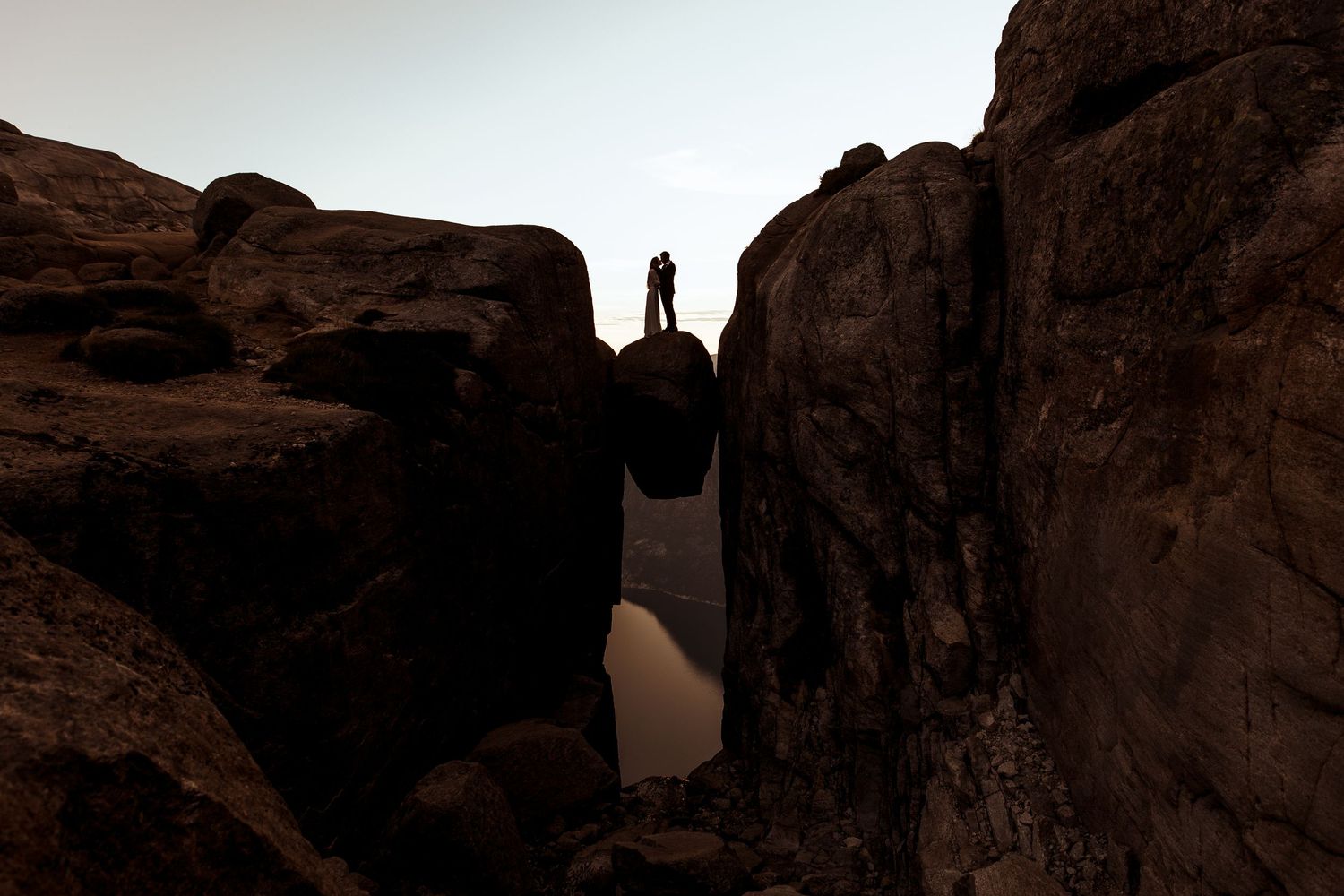 A person in white wedding dress poses elegantly against rugged desert cliffs at sunset in Tenerife.