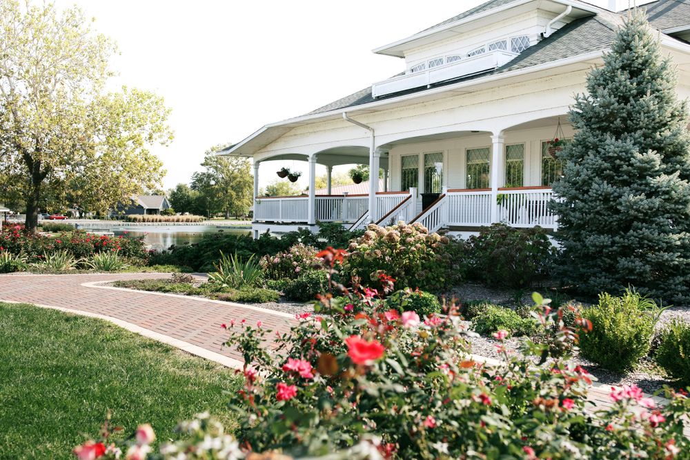 Beautiful white wedding venue with wraparound porch surrounded by colorful rose gardens.