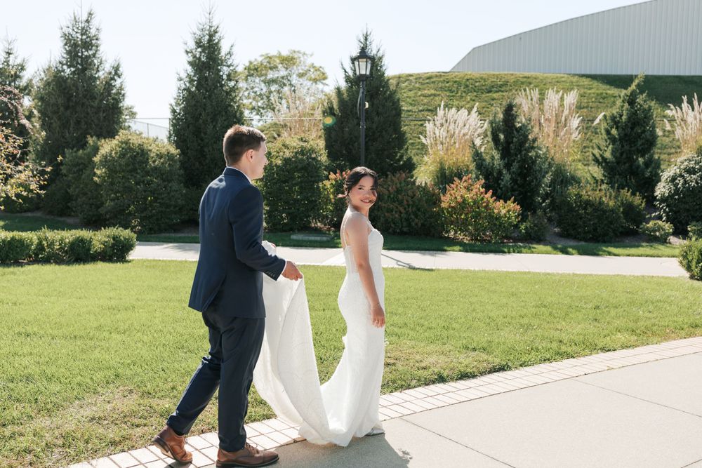 Wedding couple walking hand in hand on garden path surrounded by greenery.