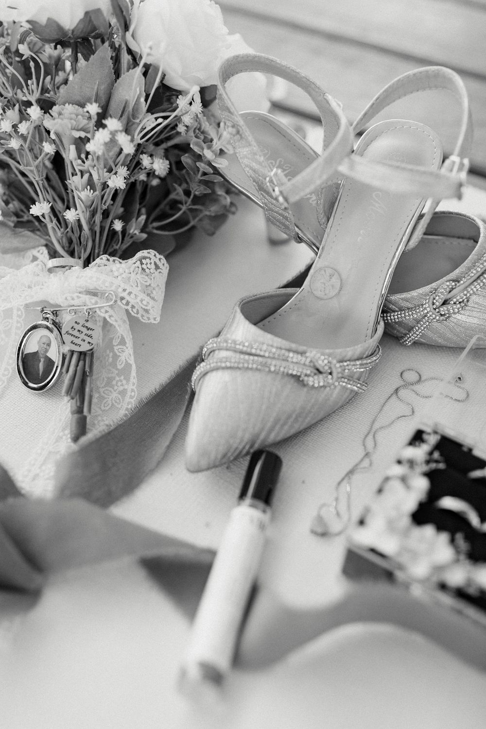 Elegant bridal shoes and floral details arranged with wedding accessories in black and white.