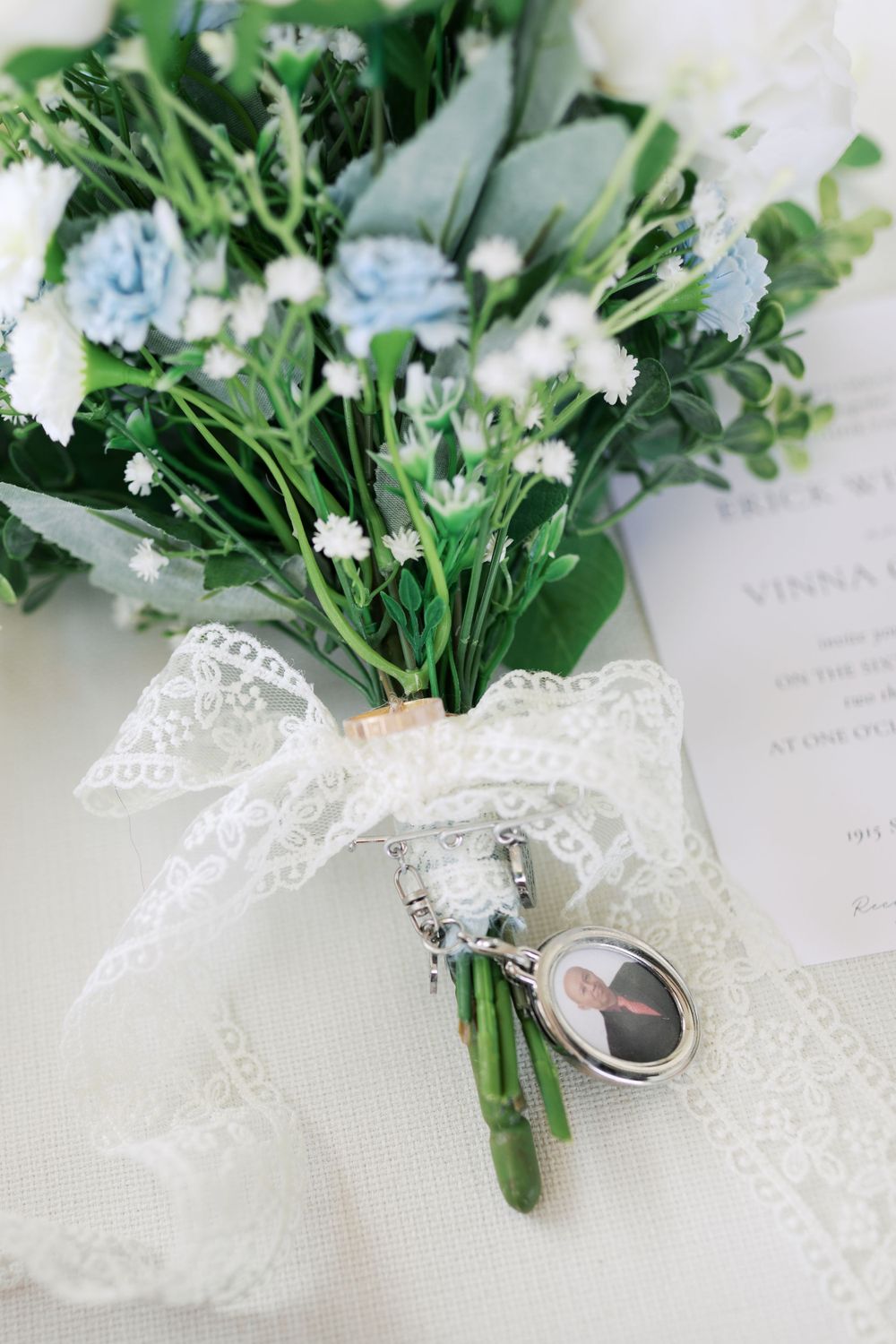 Wedding bouquet with blue flowers and lace ribbon tied around stems.
