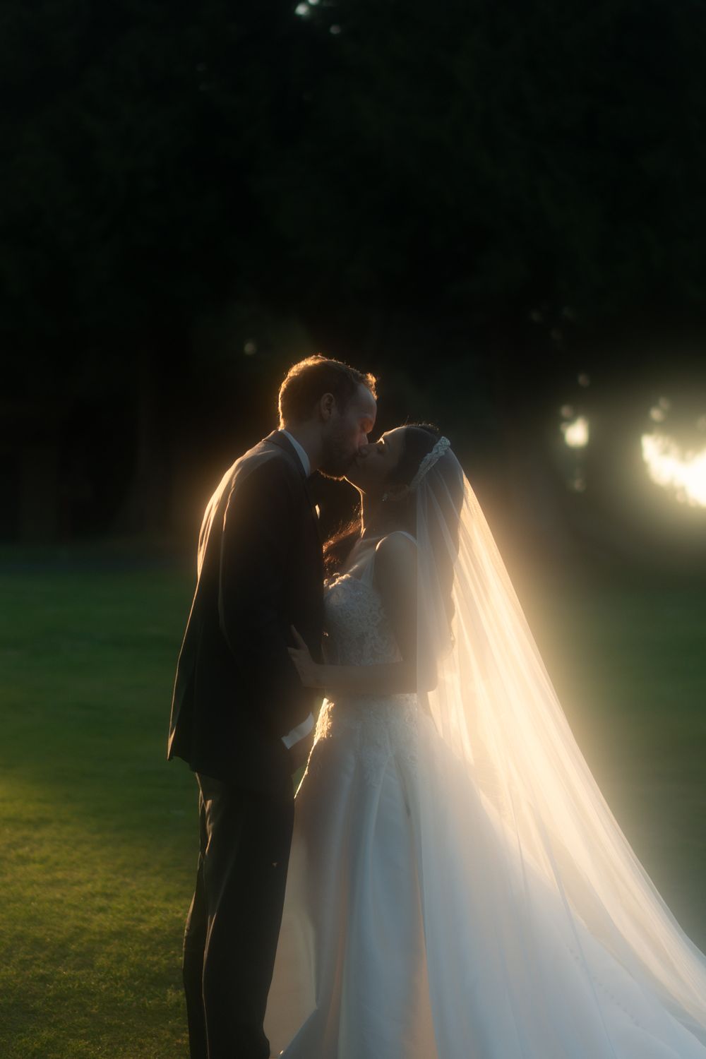 Romantic silhouette of couple in wedding attire bathed in golden evening light.
