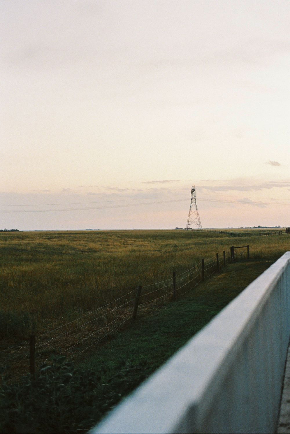 A scenic landscape view with a metal tower structure on the horizon during sunset.