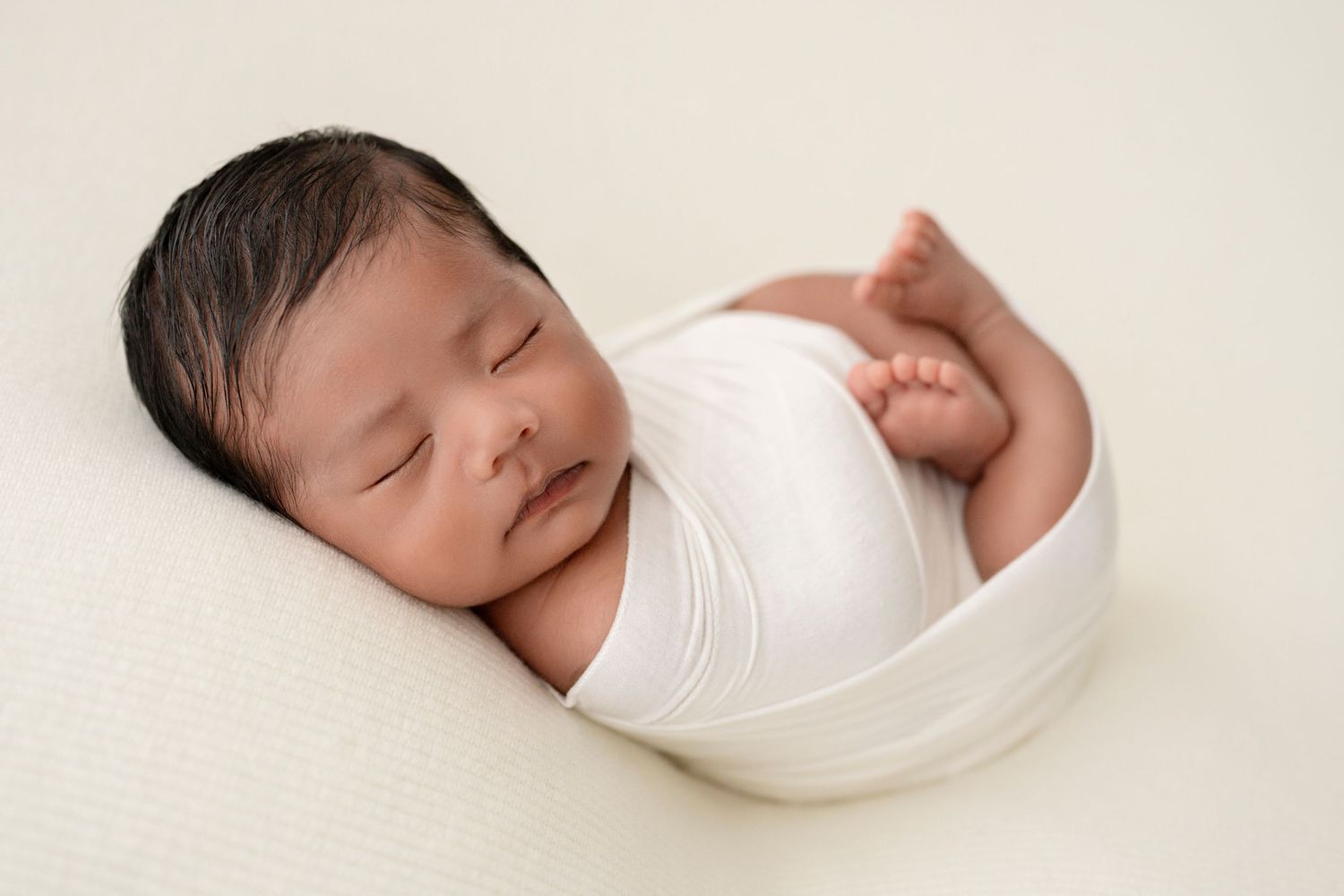 Peaceful sleeping newborn baby swaddled in white wrap
