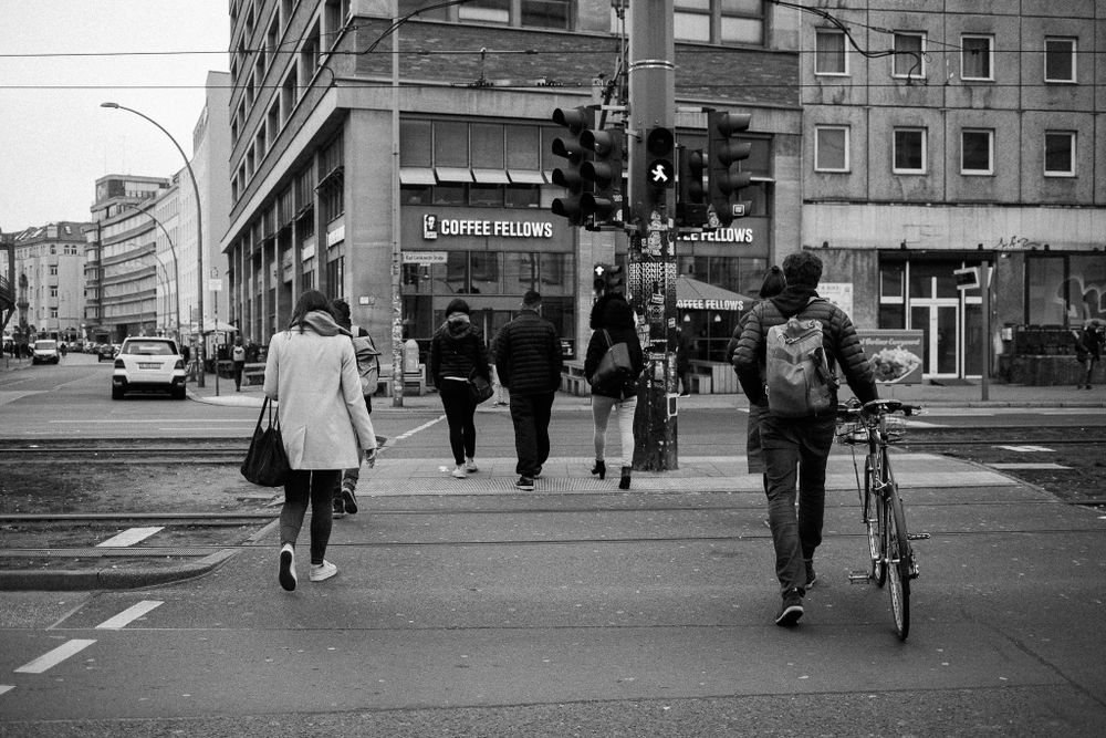 Urban street scene with pedestrians and buildings near transit station.