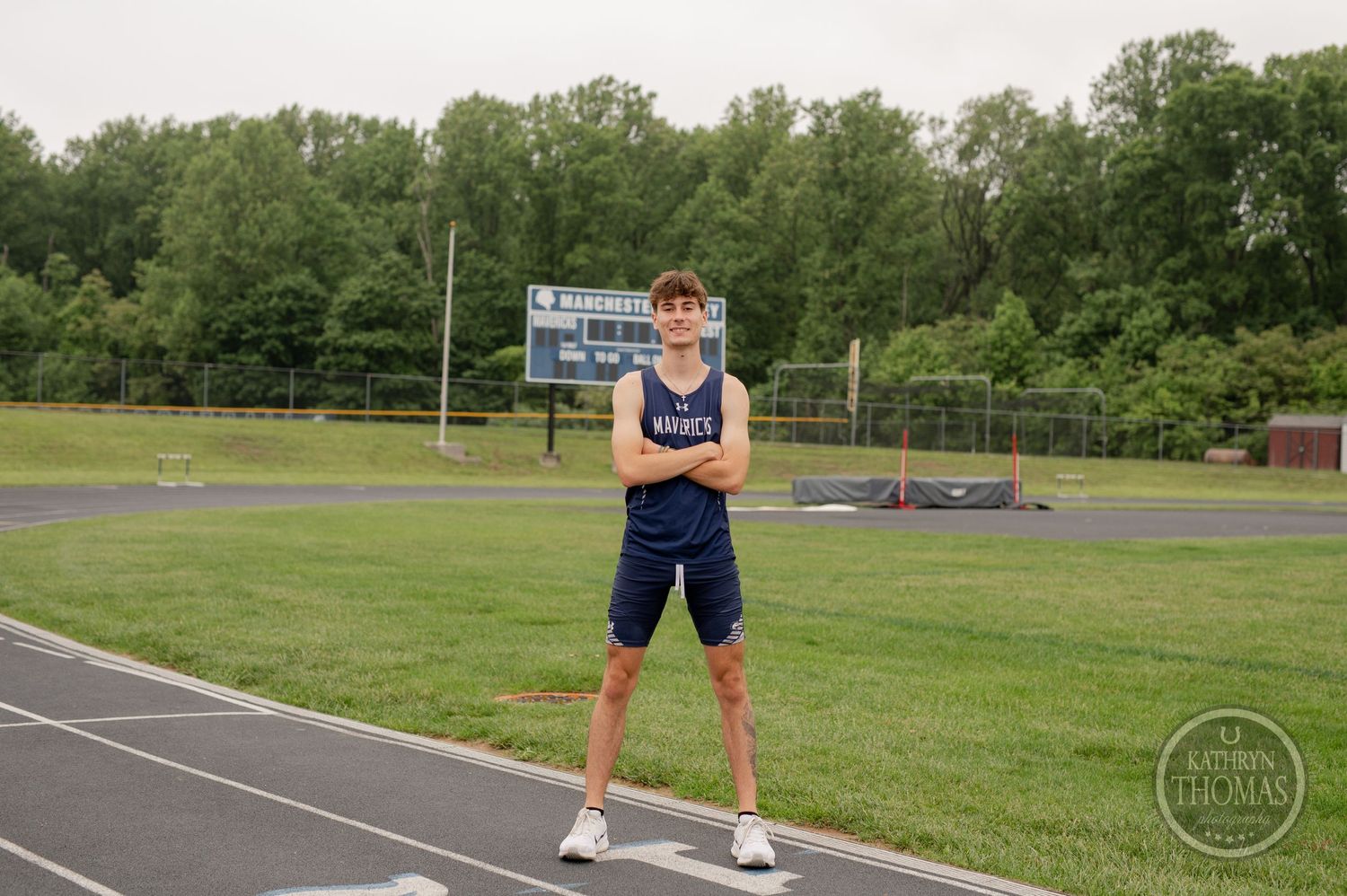 Athlete in navy blue uniform stands on outdoor track at sports field.