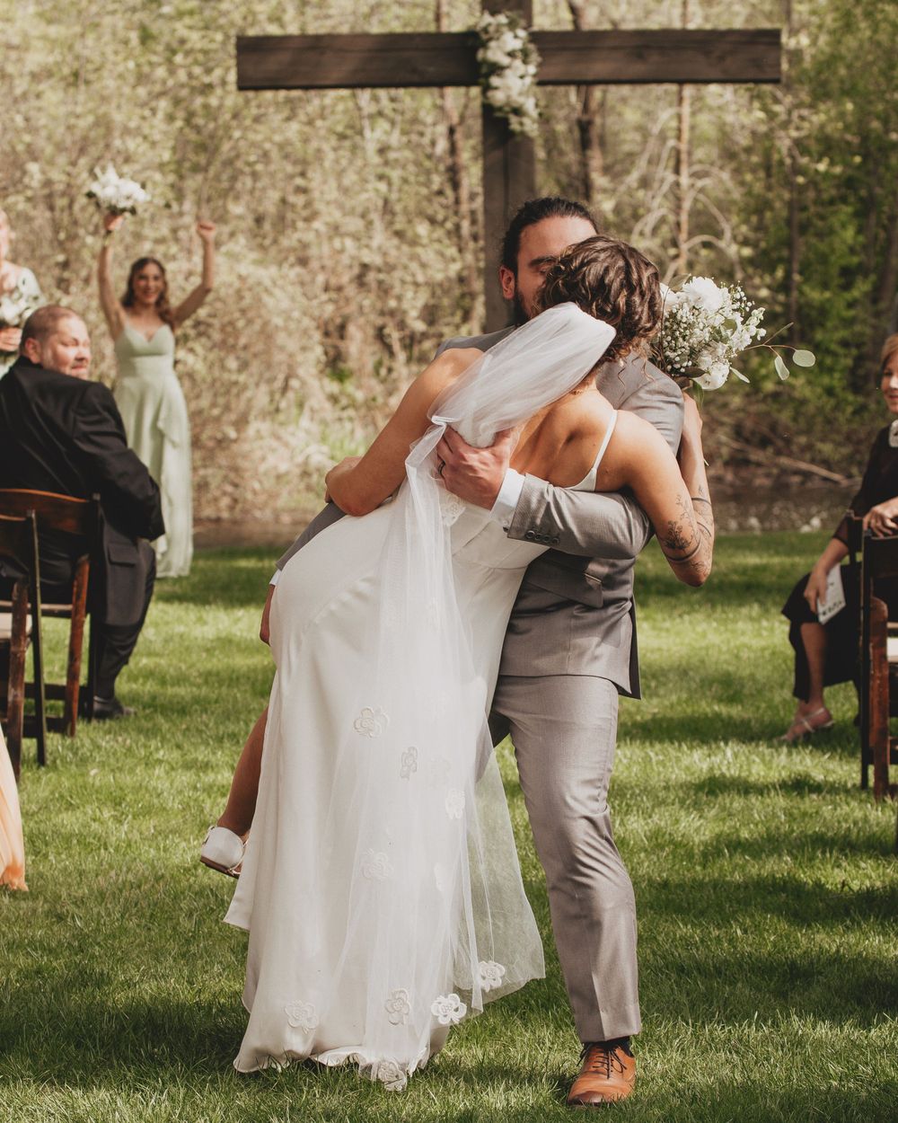 Wedding couple dancing on grass lawn with guests seated in background.