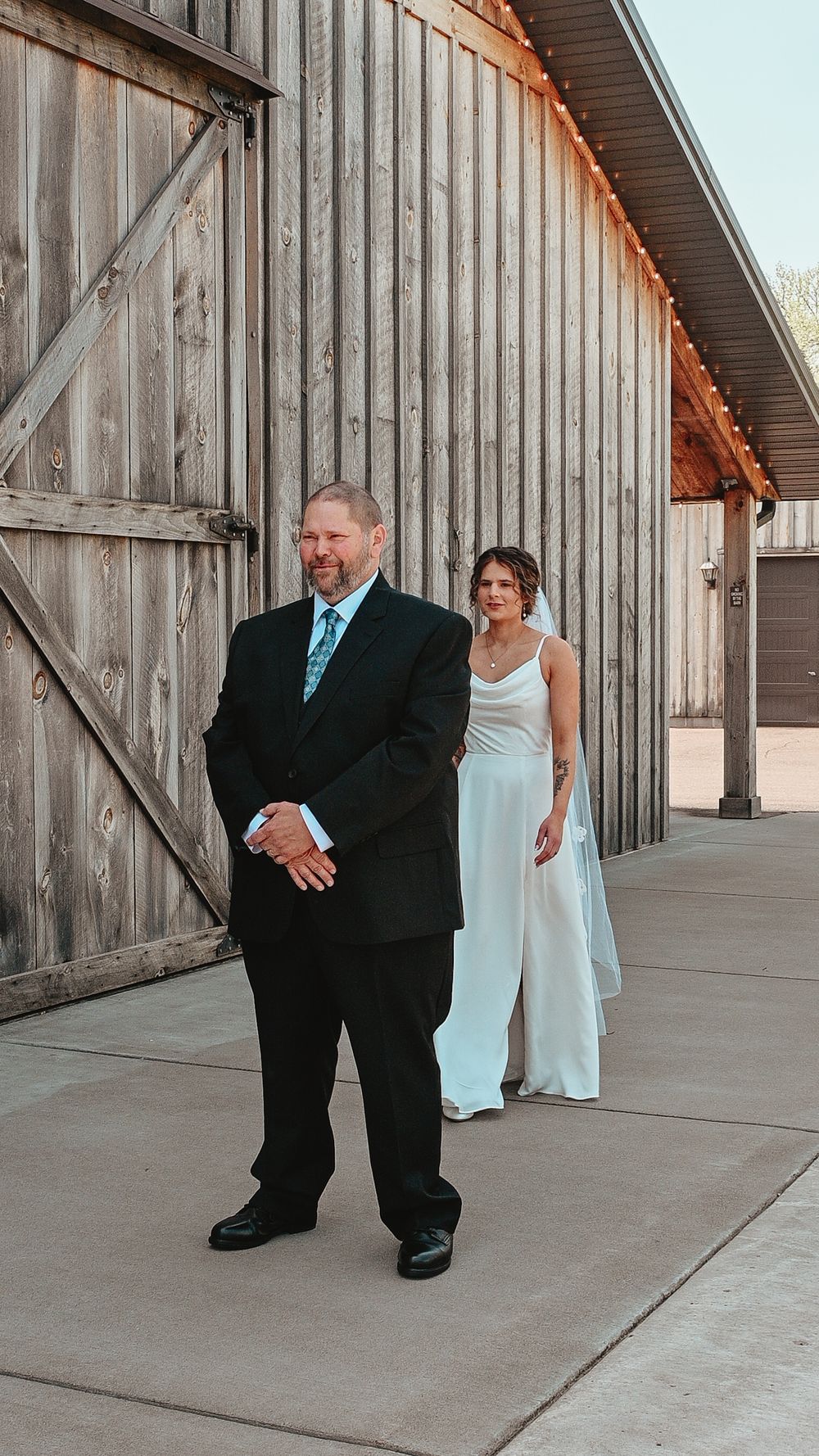 A first look wedding moment outside a rustic wooden barn.