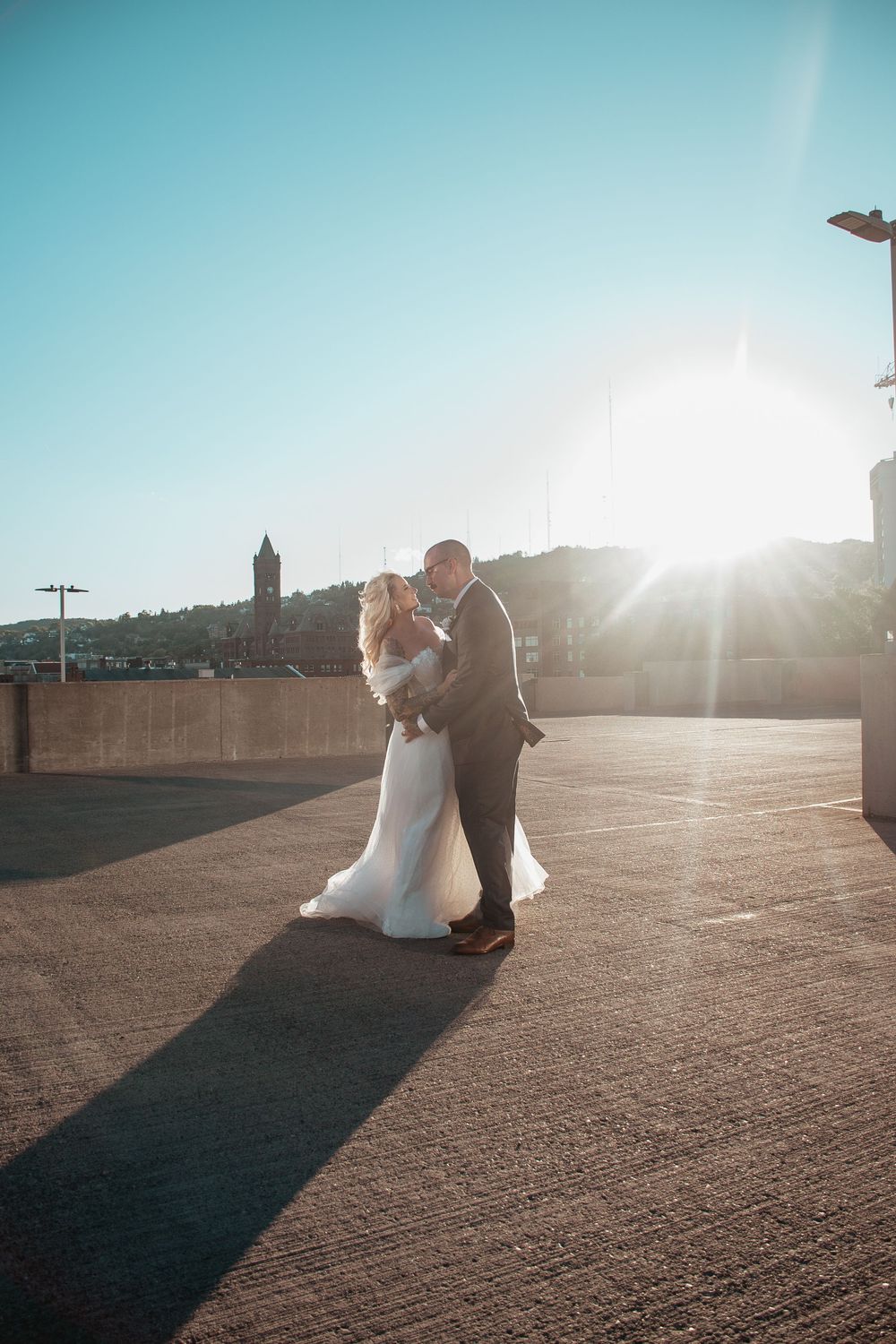 Silhouetted couple dancing at sunset against blue sky backdrop.