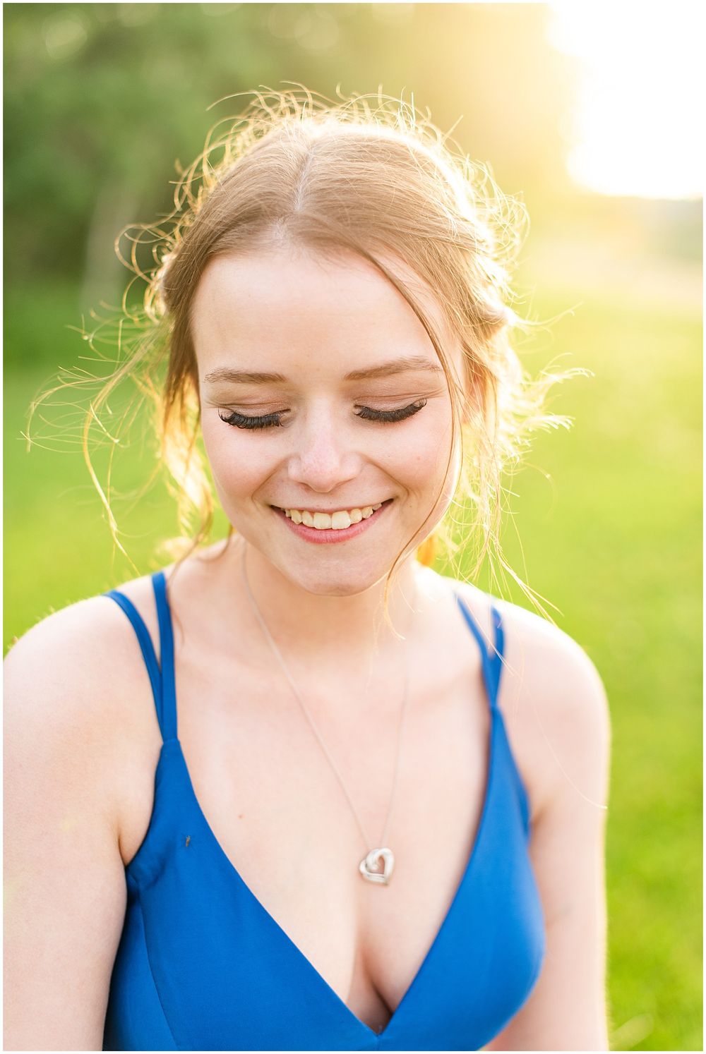 Glowing sunset portrait of person in blue dress with delicate necklace.