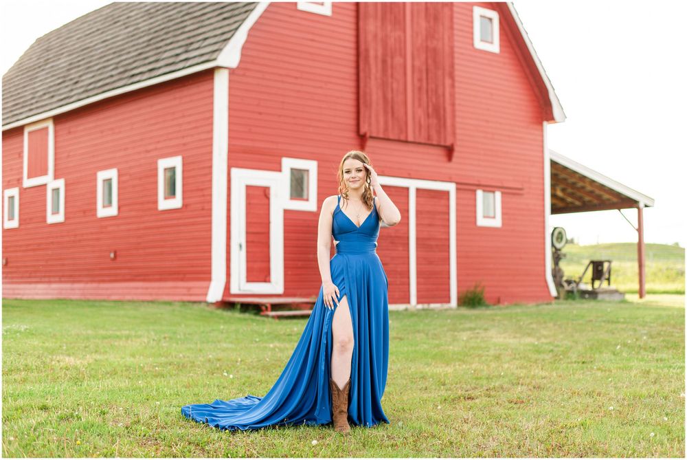 Flowing blue formal dress contrasts beautifully against classic red barn backdrop.