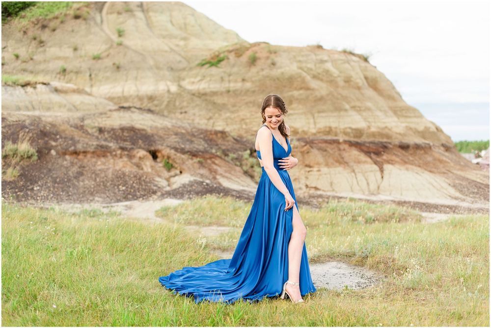 Dramatic blue gown flows in the wind against rocky badlands backdrop.