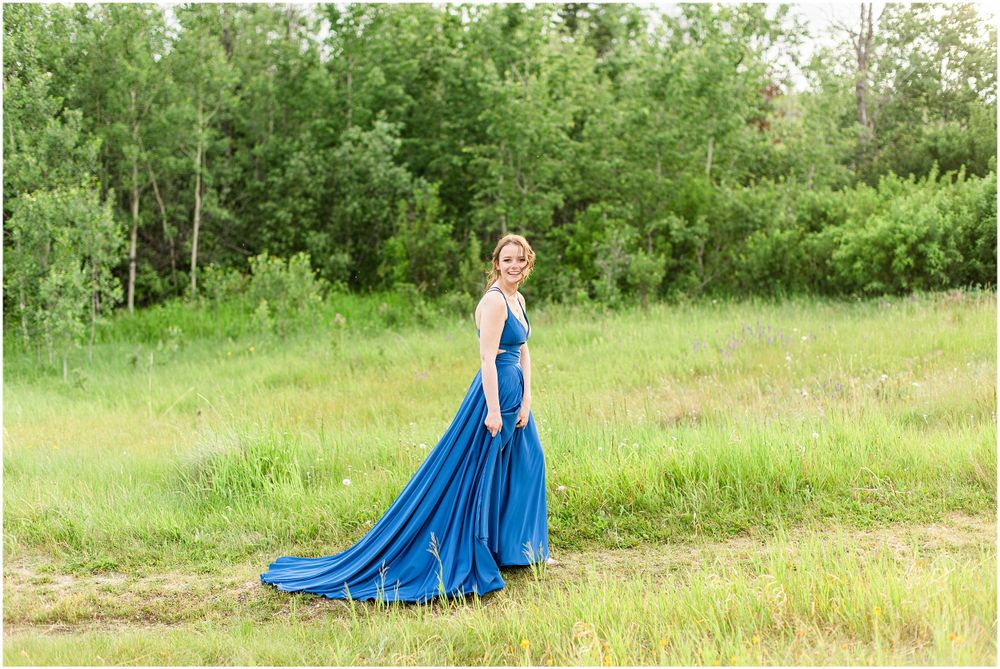 Flowing royal blue dress captured in motion against lush green summer foliage.