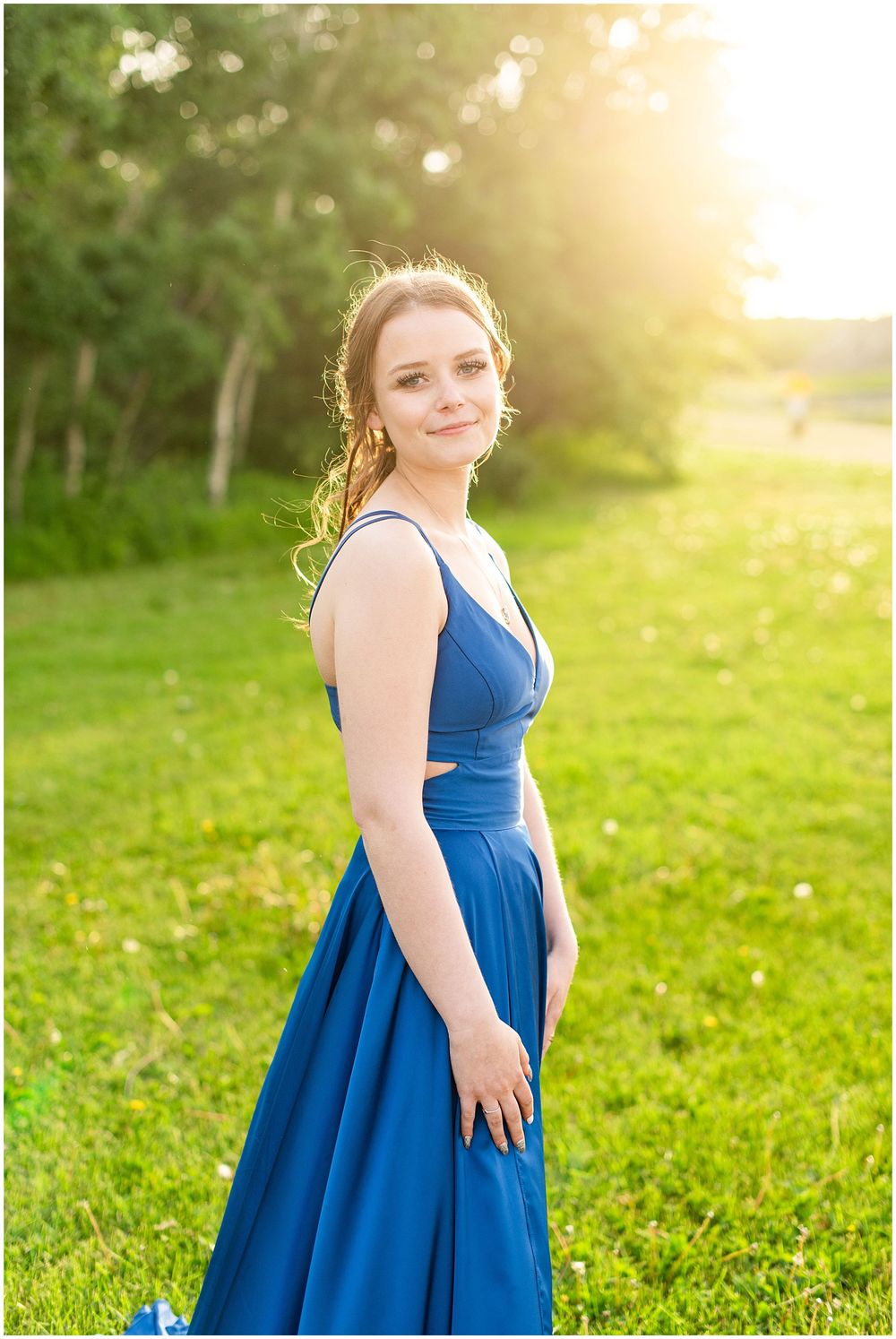 Stunning blue formal gown photographed in golden sunset light with green nature background.