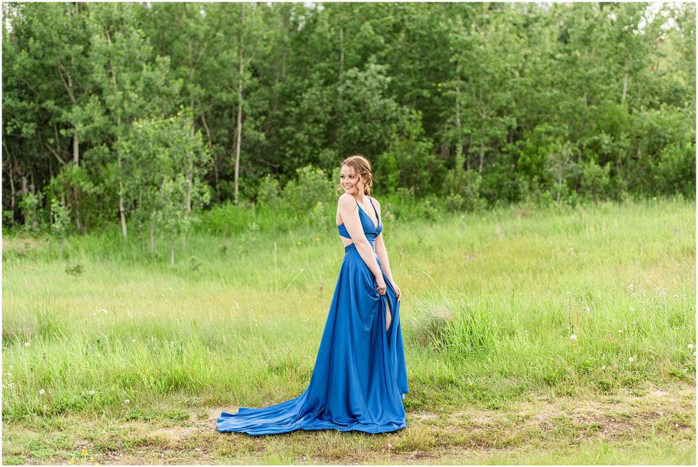 Royal blue gown with train photographed in natural meadow setting with trees.
