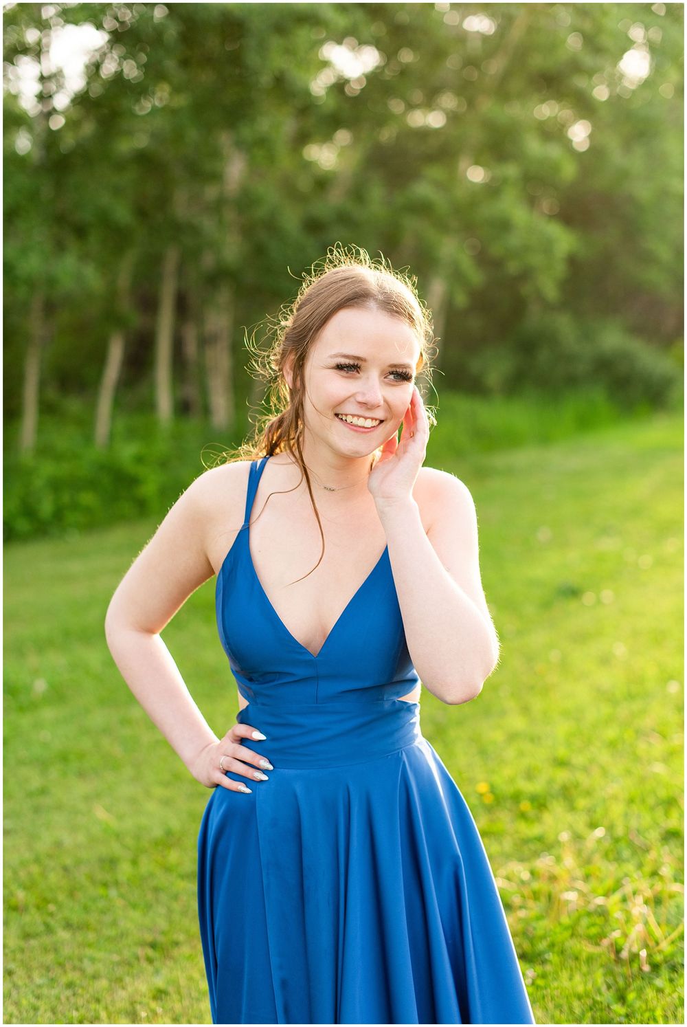A vibrant royal blue formal dress stands out against a lush green outdoor backdrop.