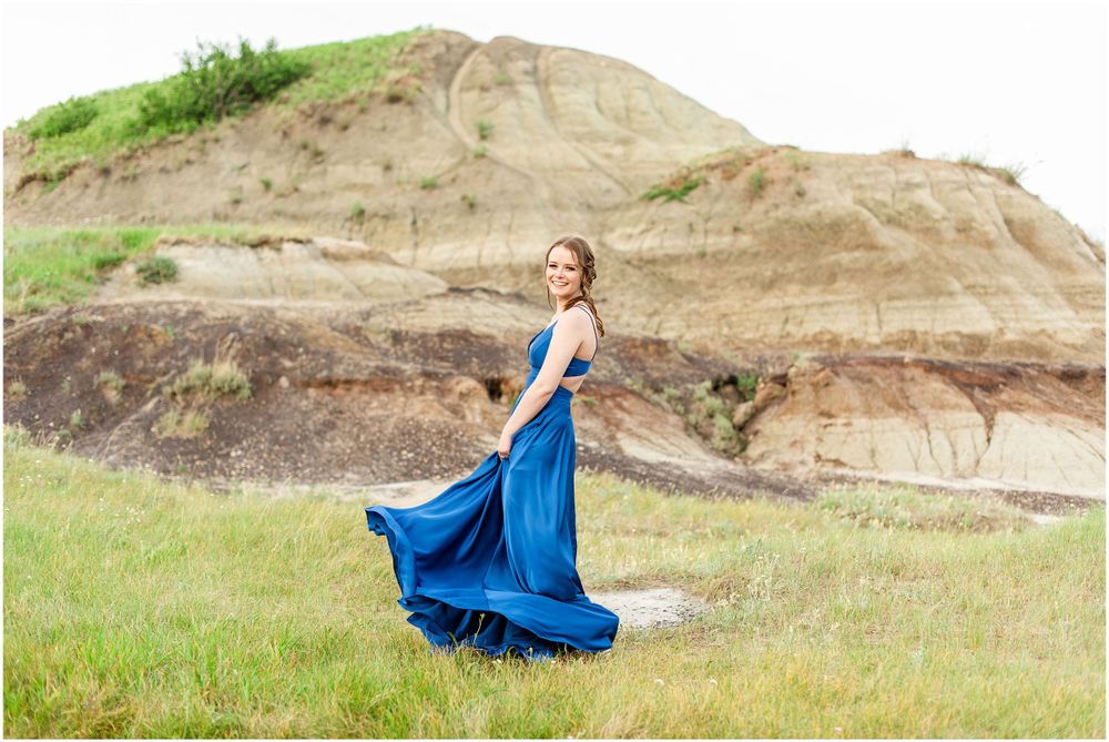 Flowing blue gown creates stunning contrast against rocky desert landscape.