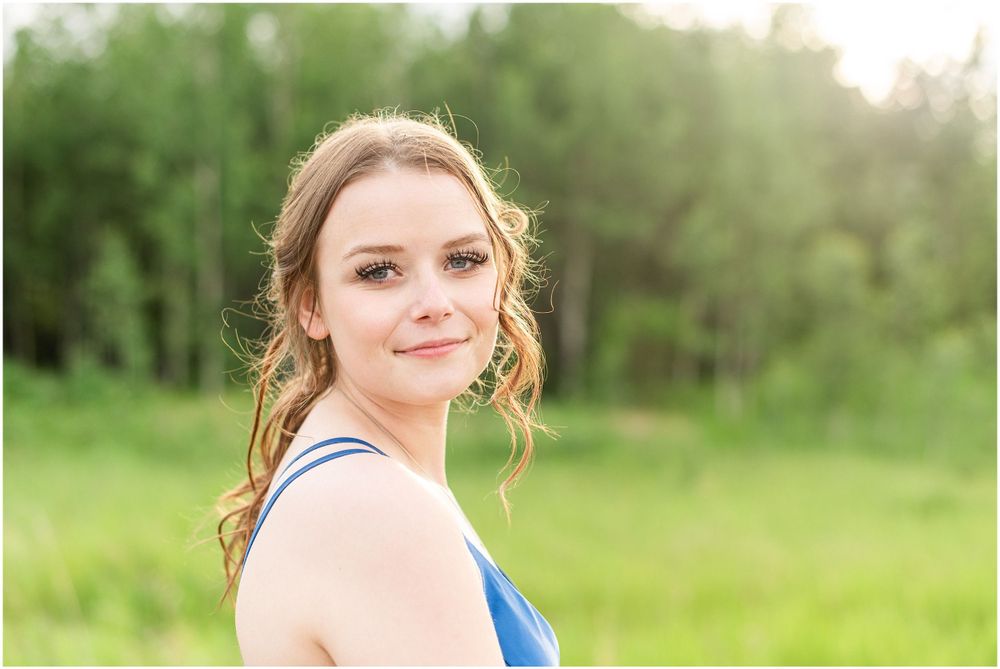 Soft golden sunlight illuminates an outdoor portrait against green foliage.