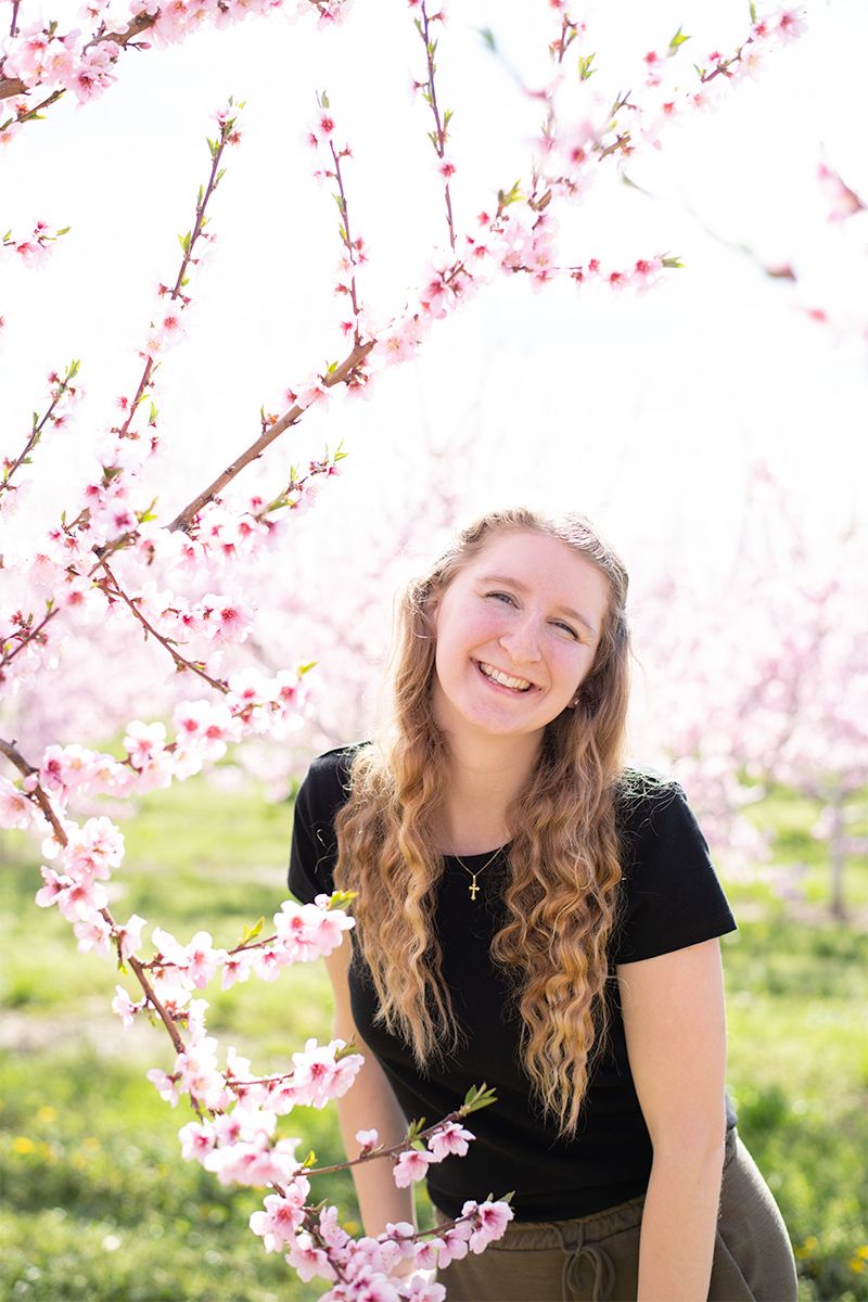 Spring portrait amidst blooming cherry blossoms and green grass.