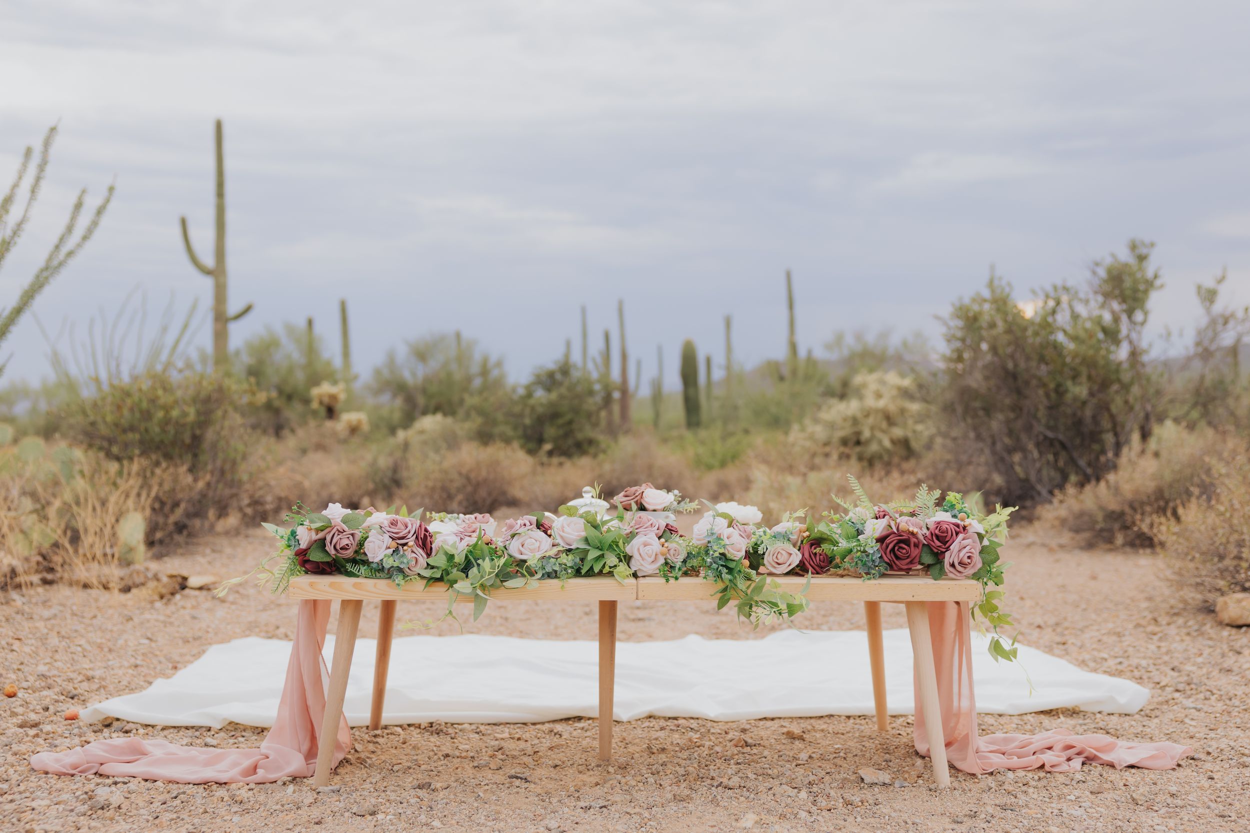 Desert landscape with wooden posts and floral arrangements set up for outdoor event.