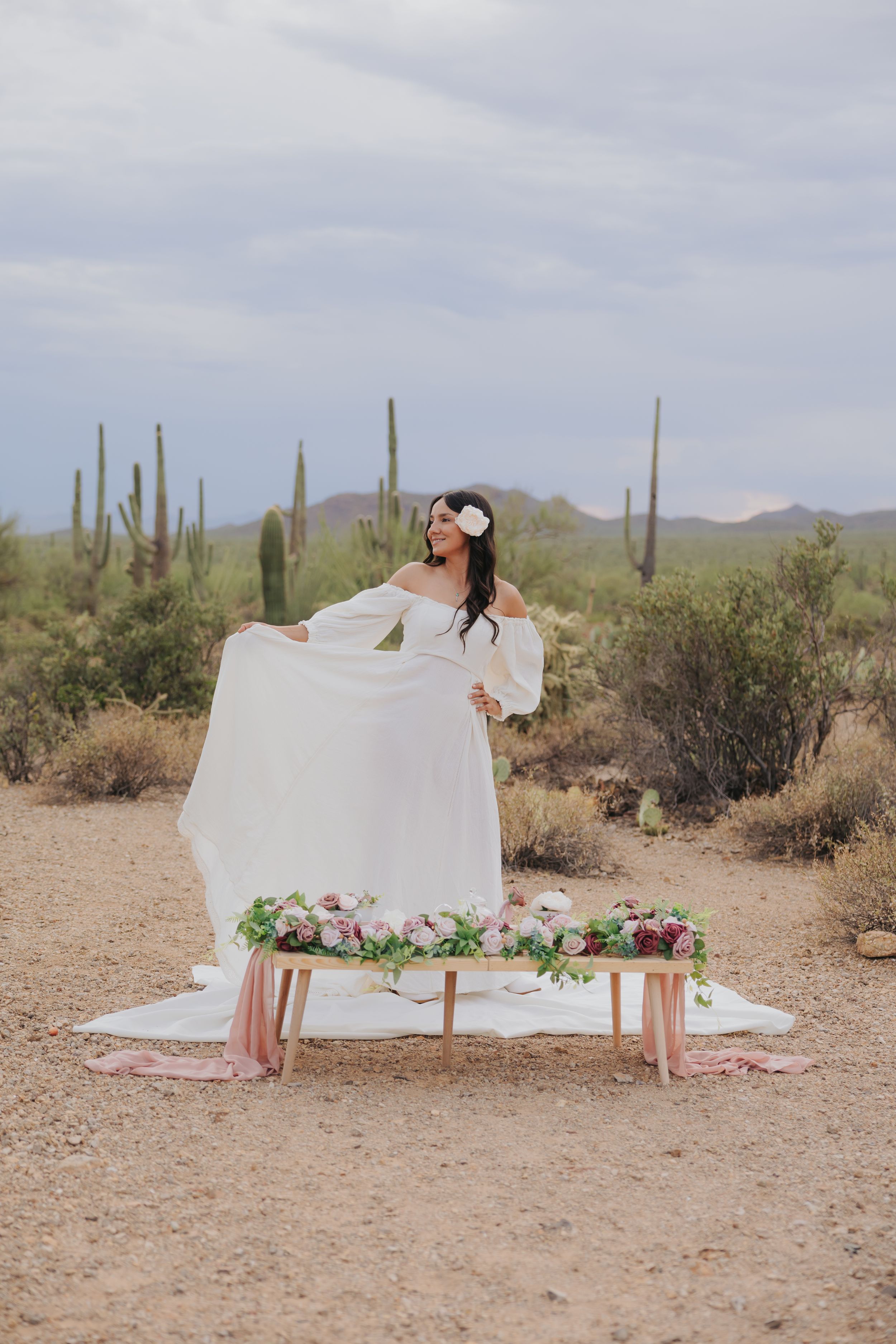 Desert photoshoot featuring elegant white dress and romantic tea party setup.