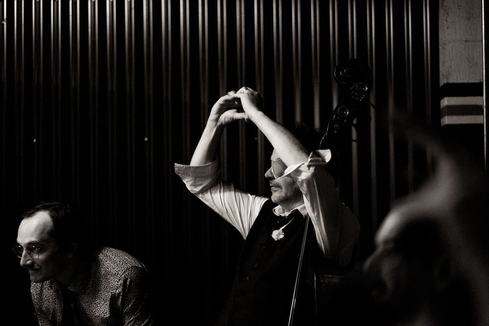 Black and white performance photo showing silhouettes against stage lighting.