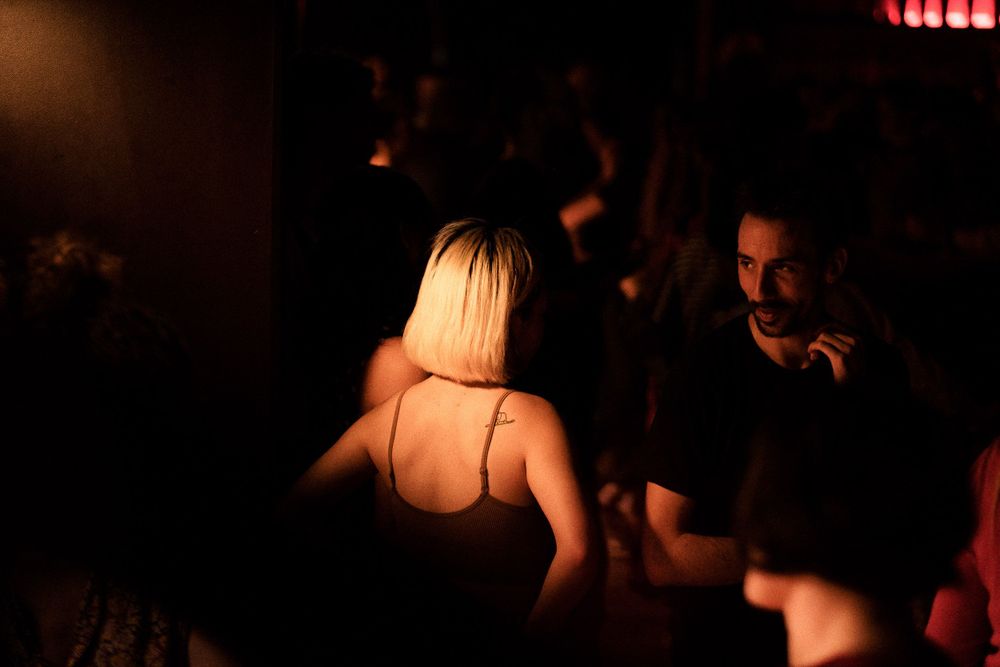 Atmospheric nightclub scene with dancers in warm dramatic lighting.