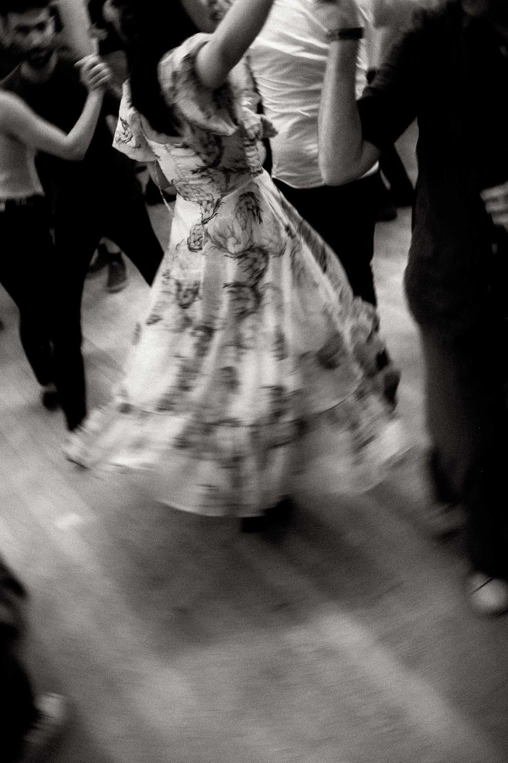 Motion-blurred black and white photo of a twirling dress on a dance floor.