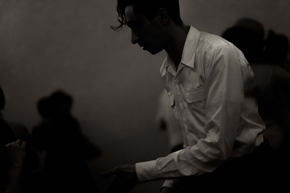 Black and white artistic photograph of dancers in a dimly lit room.