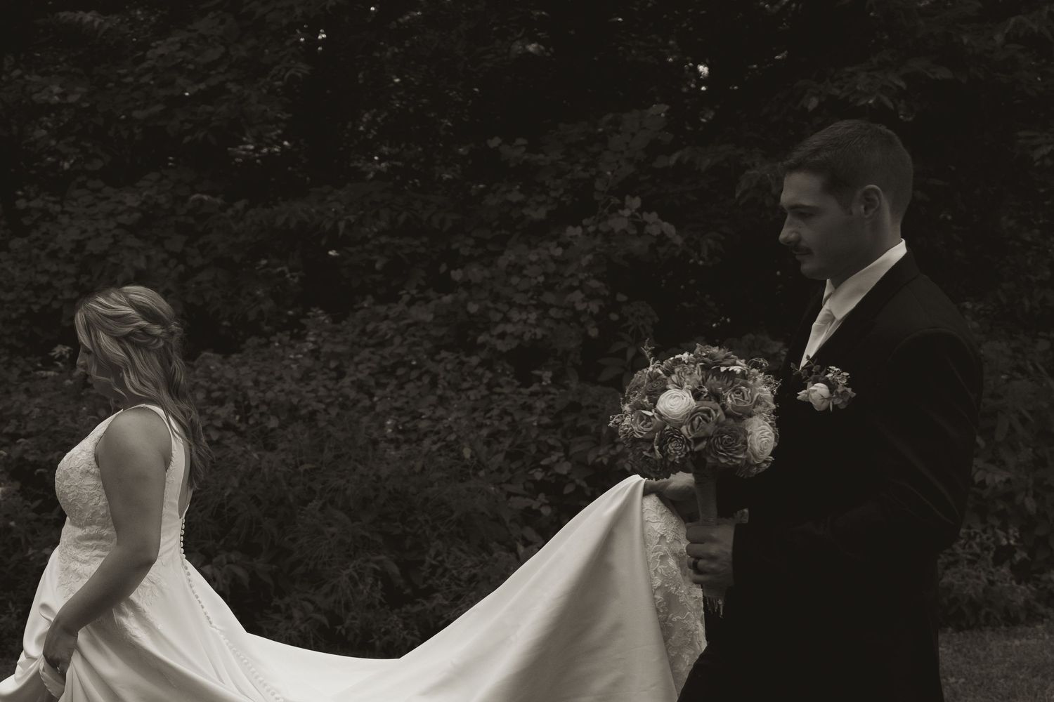 A couple shares a romantic moment in a garden setting with white floral decorations.