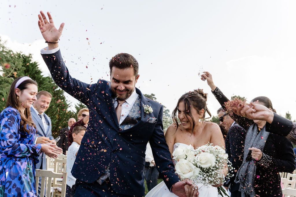 A joyous wedding celebration outdoors with confetti being thrown in the air during a festive moment.