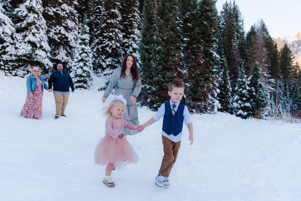 People enjoying a winter day playing in the snow with evergreen trees as backdrop.