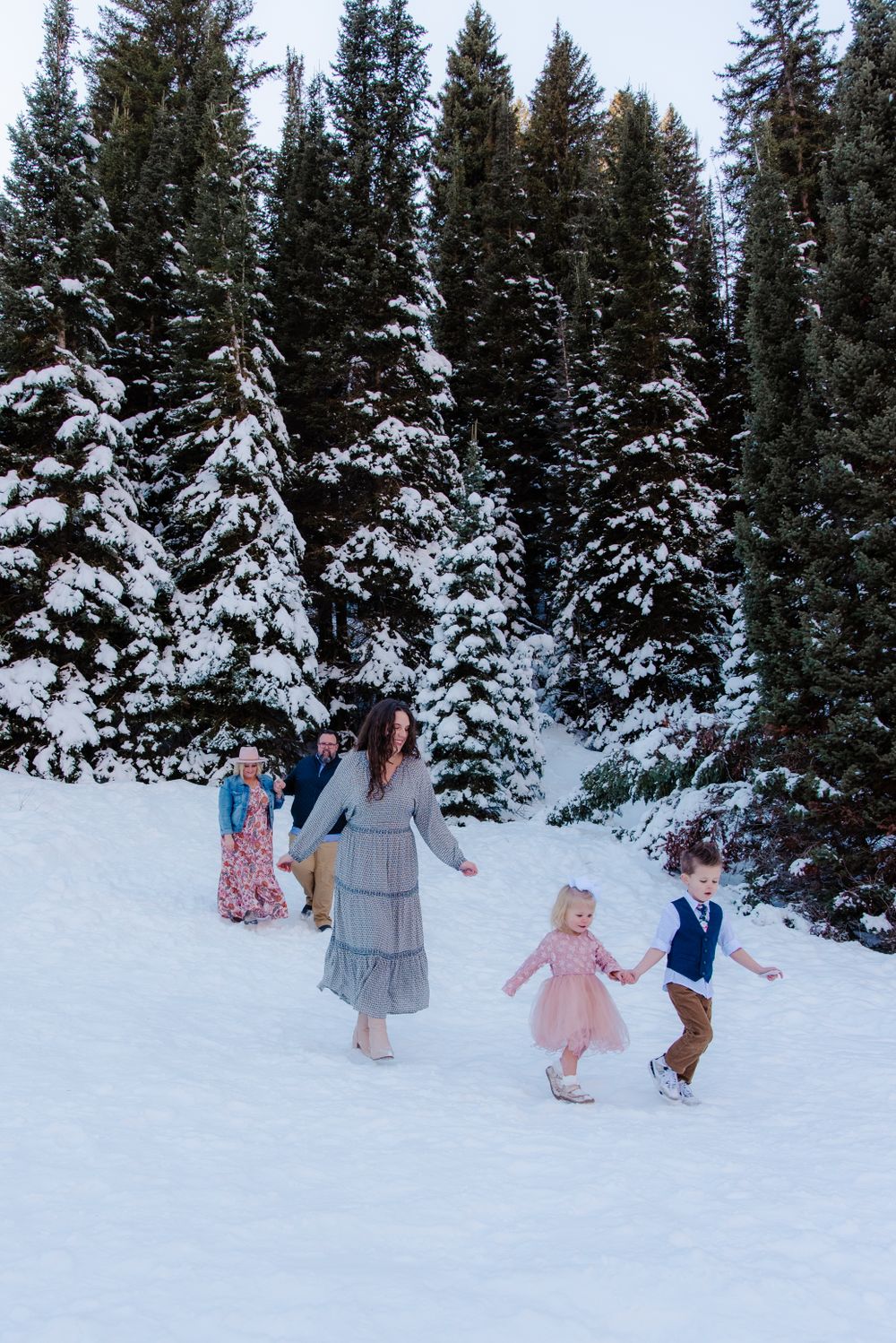 People having fun in deep snow with towering snow-covered evergreen trees behind them.