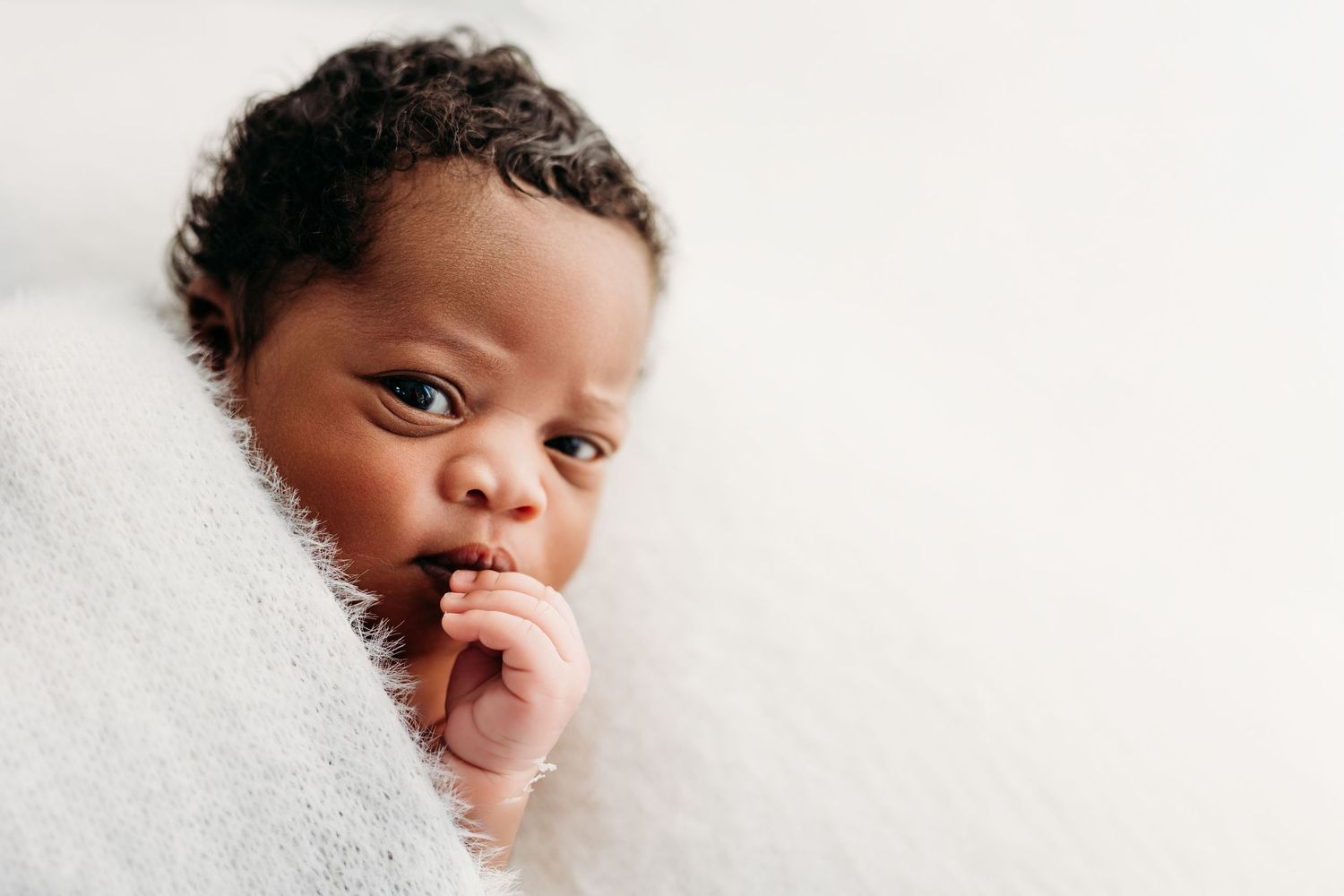A small child wrapped in a soft white blanket gazes at the camera while sucking their thumb.
Rashinphotography-Nova photographer- DMV DC