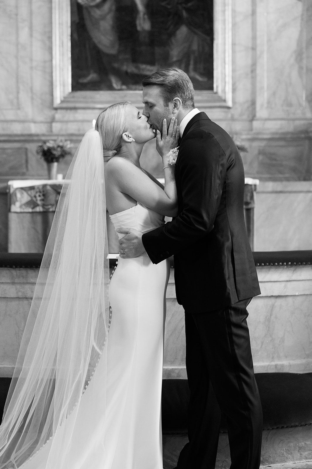 A sequence of black and white wedding photographs showing a couple sharing their first kiss as newlyweds at the altar.