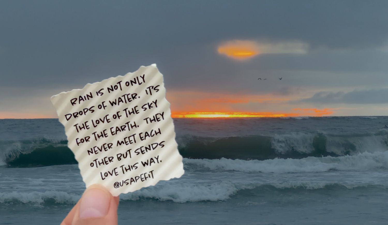 Dramatic ocean waves crash against rocky coastline during golden sunset with handwritten note in foreground.