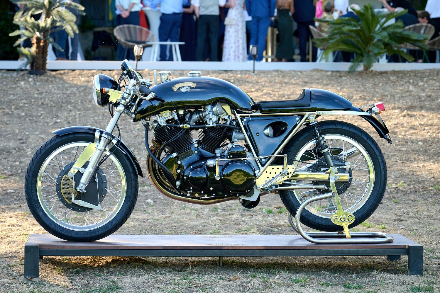 Custom vintage motorcycle with yellow accents parked on display at an outdoor show.