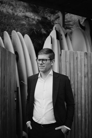 Black and white portrait series against wooden fence showing subject in formal attire and glasses.