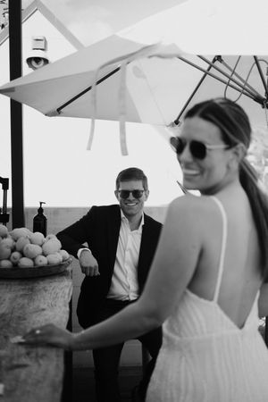 Black and white photo of a couple at an outdoor venue with a patio umbrella and fruit display.