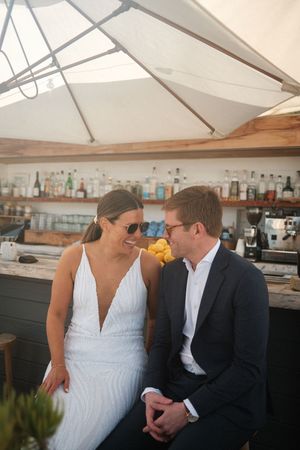 A couple sharing a moment at an outdoor bar under a white umbrella canopy.