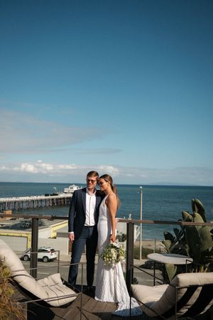 A romantic moment captured on an oceanfront terrace with lounge chairs and blue skies.