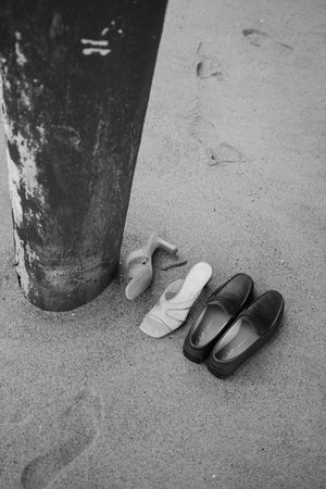 Black and white shoes lined up on concrete floor against a textured wall.
