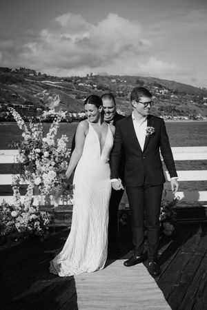 A couple shares a romantic moment on a wooden deck overlooking coastal hills in black and white.