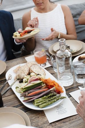 Wedding reception table set with fresh vegetables, asparagus and plates in rustic outdoor setting.