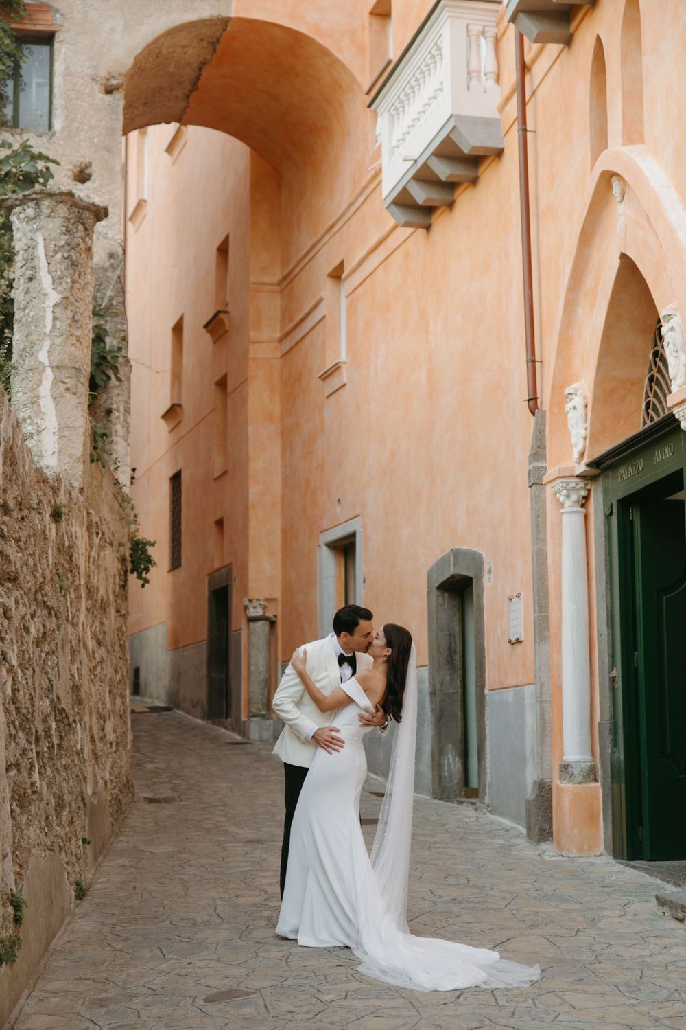 Wedding photos taken in a charming Mediterranean alley with peach-colored walls and rustic details.